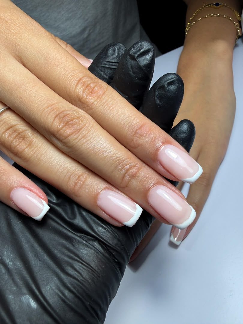 Close-up of a glossy nude manicure with clean white French tips by Chic Sphere