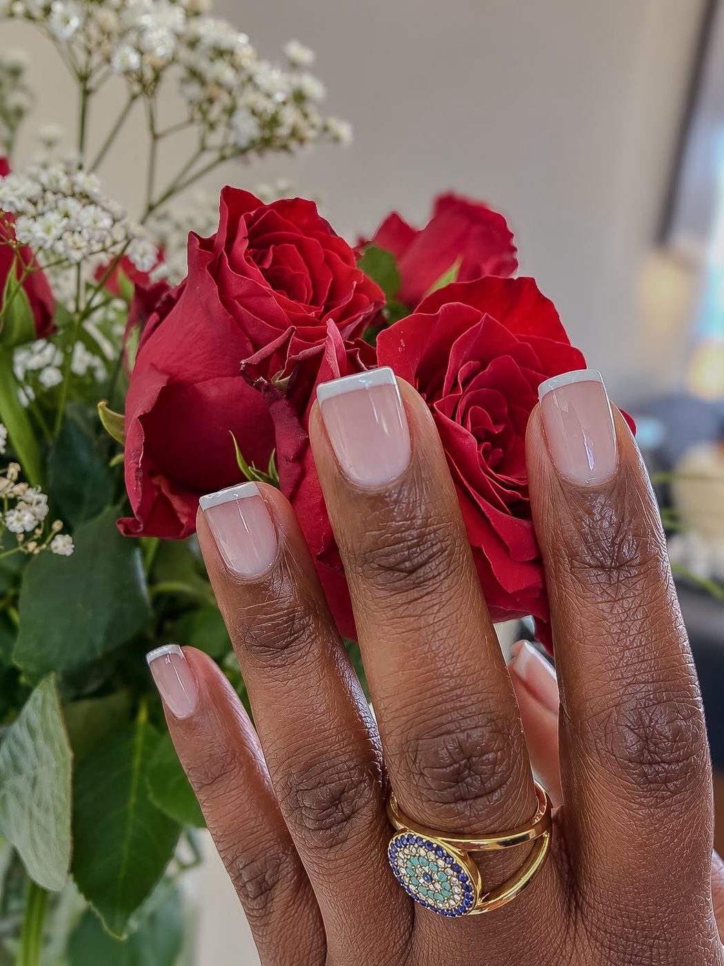 French manicure with white tips beside red roses